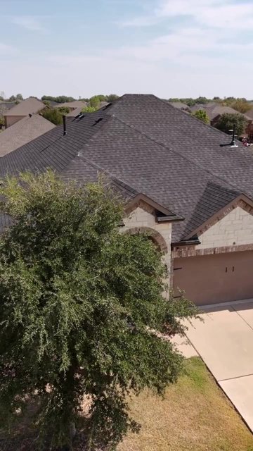 An aerial view of a residential home and its surrounding neighborhood.